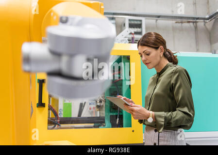 Businesswoman contrôler un robot industriel dans une entreprise de haute technologie Banque D'Images