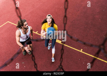 Jeune homme et femme jouant au basket-ball sur terrain de basket-ball Banque D'Images