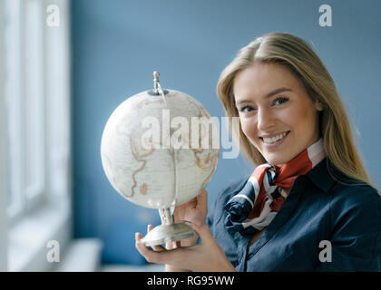 Portrait of smiling young stewardess with globe Banque D'Images