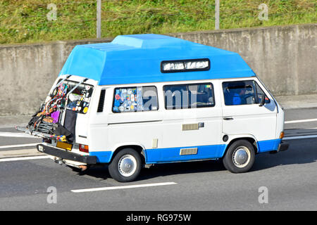 Et côté arrière de VW bleu et blanc hi-top transporter le camping-car & driver modification porte vélo pour le camping articles divers exposés sur l'arrière du véhicule autoroute britannique Banque D'Images