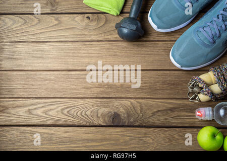 Condition physique et mode de vie sain et actif en arrière-plan dieting concept. Haltère, saut de cordes, les pommes, les chaussures de sport, bouteille d'eau et les pommes vertes sur le bois b Banque D'Images