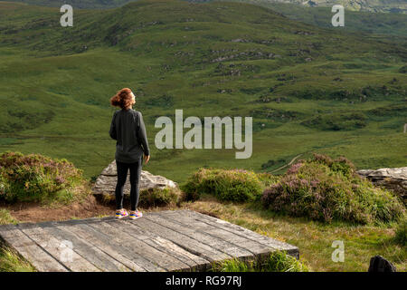 Jeune randonneur sur une plate-forme d'observation en admirant la vue panoramique sur la Old Kenmare Road depuis le sentier de randonnée de Torc Mountain à Killarney, en Irlande Banque D'Images