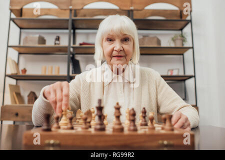 Senior woman sitting at table, jouer aux échecs et à la maison Banque D'Images