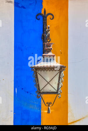 Photographie d'une vieille lampe fer forgé streep contre un jean bleu et jaune mur de plâtre pris dans le village médiéval d'Obidos, Portugal. Banque D'Images