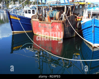 Certains des bateaux de pêcheurs qui pêchent dans les eaux dans l'ouest de l'Écosse, se trouvent amarrés à la jetée dans le village de Tarbert, le Loch Fyne en Ecosse. Leurs arcs et les coques sont reflète dans l'eau. Alan Wylie/Alamy © Banque D'Images