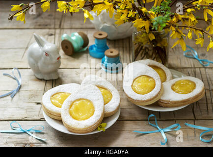 Composition de Pâques avec des cookies en forme d'œuf rempli de lait caillé de citron, lapin, bouquet de forsythia et d'arcs. Focus sélectif. Banque D'Images