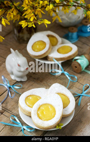 Composition de Pâques avec des cookies en forme d'œuf rempli de lait caillé de citron, lapin, bouquet de forsythia et d'arcs. Focus sélectif. Banque D'Images