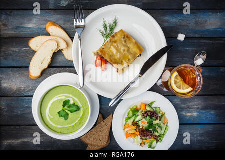 Le déjeuner ensemble. Lasagne, soupe et légumes salade fraîche, servi avec les couverts. Banque D'Images