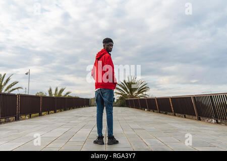 Jeune homme noir standing outdoors, looking over shoulder Banque D'Images