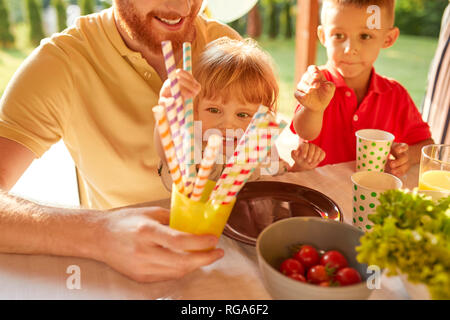 Les enfants prenant des pailles une garden party Banque D'Images