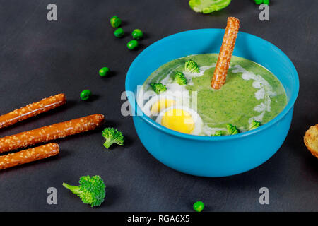 Crème de brocoli soupe aux pois verts et avec des œufs durs et des bretzels, fond en bois foncé Banque D'Images