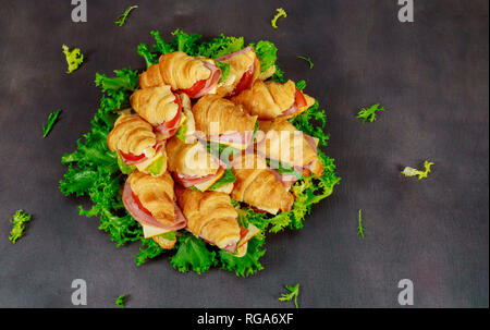 Un croissant avec du fromage et de la saucisse aux herbes. sur fond sombre Banque D'Images