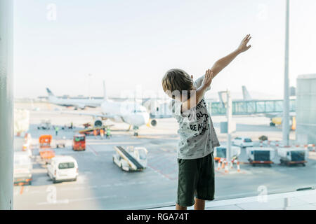 L'Espagne, l'aéroport de Barcelone, garçon en aire de départ, en faisant semblant de voler Banque D'Images