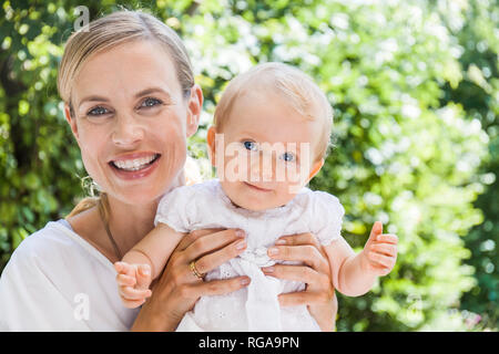 Portrait of happy mother holding her baby girl outdoors Banque D'Images
