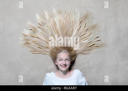 Portrait of smiling girl lying on floor avec des épis de blé sur les cheveux jusqu'à la Banque D'Images