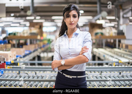 Portrait of smiling woman at conveyor belt in factory Banque D'Images