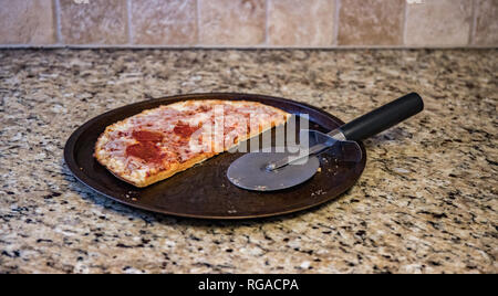 La moitié d'un des restes de pizza surgelée jetée sur le comptoir. Banque D'Images