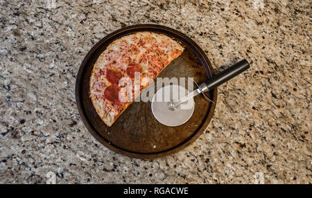 La moitié d'un des restes de pizza surgelée jetée sur le comptoir. Banque D'Images