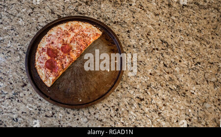 La moitié d'un des restes de pizza surgelée jetée sur le comptoir. Banque D'Images