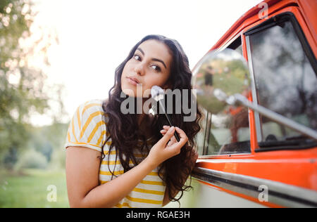 Une jeune fille à la recherche de miroir et d'appliquer le maquillage sur un roadtrip à travers la campagne. Banque D'Images