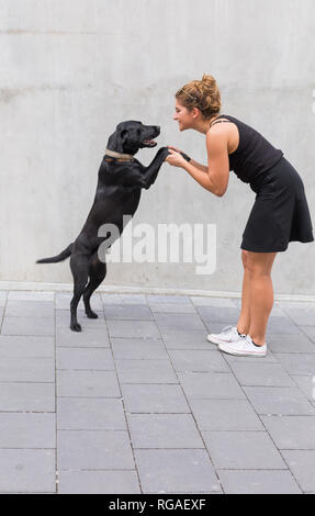 Jeune femme vêtue de noir avec son chien noir Banque D'Images