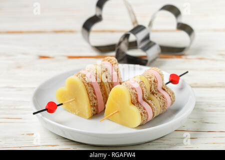 Mini sandwiches pain jambon fromage parmesan en brochettes sous la forme de cœurs. Le jour de la Saint-Valentin. Le petit-déjeuner pour les proches. Focus sélectif et copy space Banque D'Images