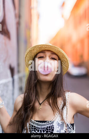 Portrait of young woman blowing bubble gum Banque D'Images