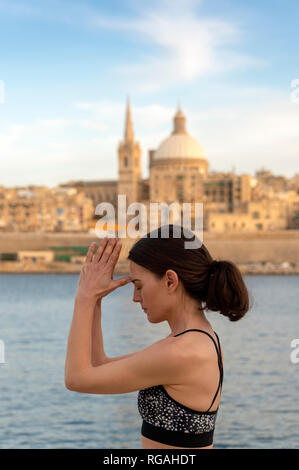 Femme spirituelle en yoga méditation troisième œil posent avec la Valette cityscape toile Banque D'Images