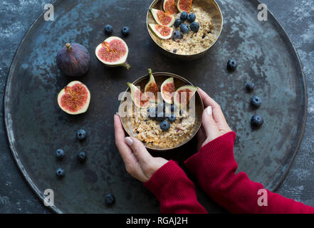 Woman's hands holding bol de porridge de tranches de figues, myrtilles et baies séchées Banque D'Images
