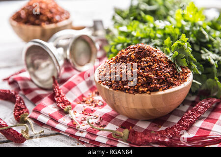 Piments séchées et broyées en bois avec le persil dans bowles herbes. Banque D'Images