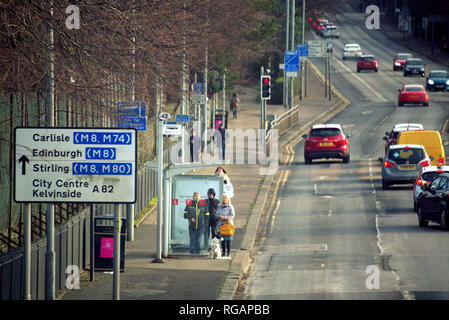 Les gens qui attendent à un bus haut avec un fort trafic sur Great Western Road, A82, Glasgow, Écosse, Royaume-Uni Banque D'Images