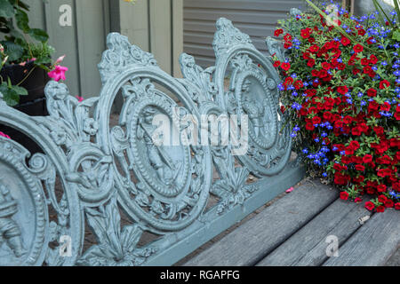 Gros plan d'une photo de détail un acier et bois banc de parc avec un panier de fleurs. Banque D'Images