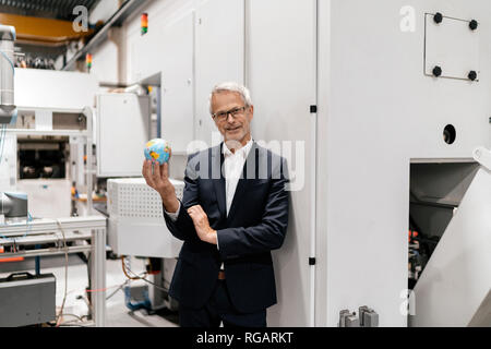 Manager dans une entreprise de haute technologie holding globe peu, smiling Banque D'Images