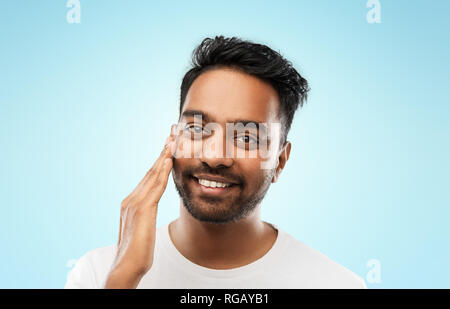 Smiling indian man toucher son visage Banque D'Images