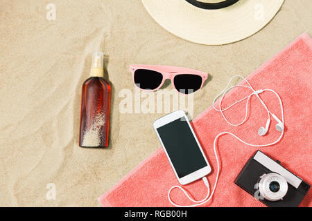 Smartphone, appareil photo, serviette, chapeau et nuances on beach Banque D'Images