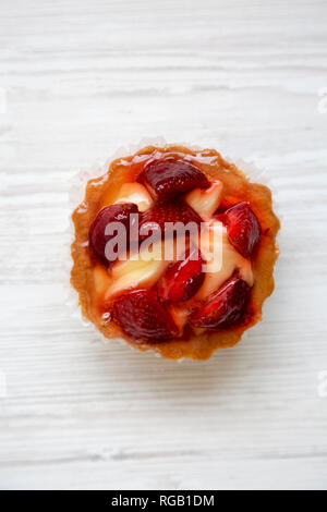 Fromage à la crème aux fraises tartelettes sur la surface en bois blanc, vue du dessus. Libre. Banque D'Images