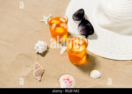 Cocktails, chapeau de soleil et lunettes de soleil sur le sable de la plage Banque D'Images