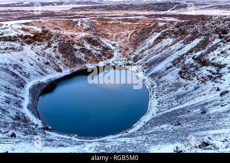 Kerid cratère volcanique et le lac, Kerid, Grimsnes, Islande. Il y a des gens de tourisme méconnaissable avec le flou de marcher sur le bord du cratère. Banque D'Images