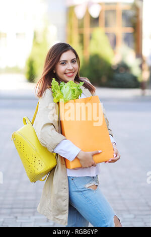 Belle jeune fille avec orange sac de papier avec des légumes, verts et chou de Pékin smiling outdoors. Banque D'Images