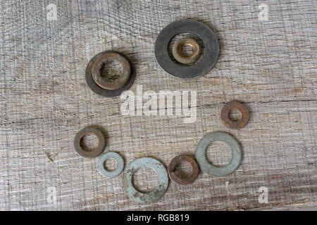 Un visage heureux disposés de rusty rondelles métalliques, placés sur un morceau de bois gris clair. Banque D'Images