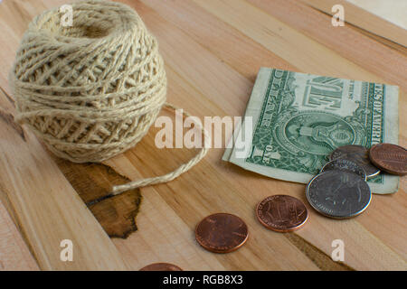 US changement de poche sur le dessus d'un dollar plié à côté d'une pelote de ficelle placé sur une table en bois. Banque D'Images