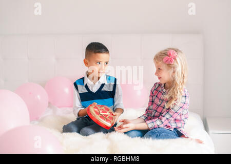 Portrait de groupe de deux adorables enfants mignon caucasienne de manger des bonbons en forme de coeur. Garçon Fille donner cadeau chocolat présents pour célébrer la Saint-Valentin. Banque D'Images