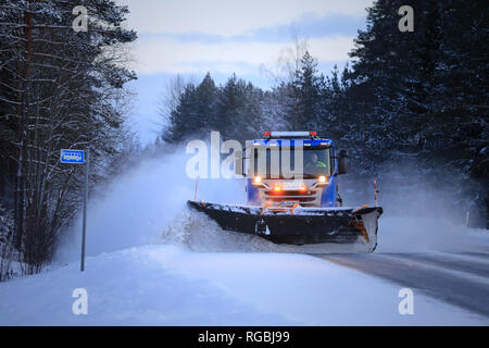 Salo, Finlande - le 18 janvier 2019 : Blue Scania Truck équipé d'un chasse-neige neige efface l'arrêt de bus par la route dans le sud de la Finlande au crépuscule d'hiver. Banque D'Images