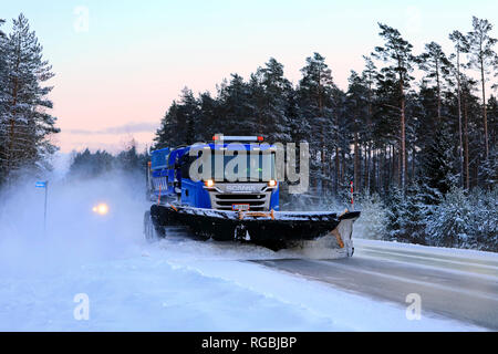 Salo, Finlande - le 18 janvier 2019 : Blue Scania Truck équipé d'un chasse-neige dégage la route enneigée dans le sud de la Finlande au crépuscule d'hiver. Banque D'Images