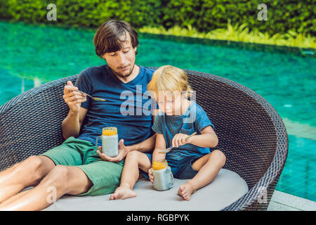 Père et fils manger le dessert avec chia seeds et de mangues à la piscine le matin. la saine alimentation, l'alimentation, les régimes végétariens et personnes concept Banque D'Images