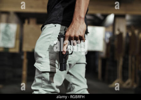 Close-up de l'homme tenant un pistolet dans un intérieur de tir Banque D'Images