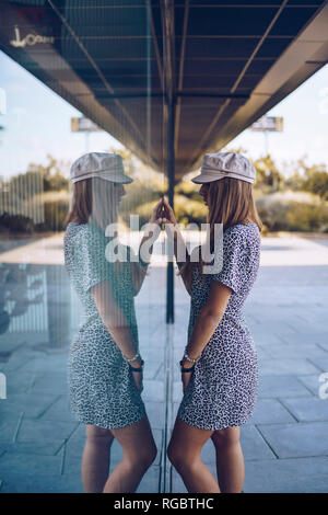 Belle jeune femme en robe léopard reflétée dans la vitre Banque D'Images