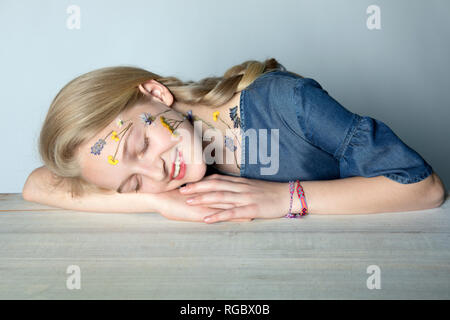 Portrait of smiling blonde avec tatouage de fleurs pressées sur son visage Banque D'Images