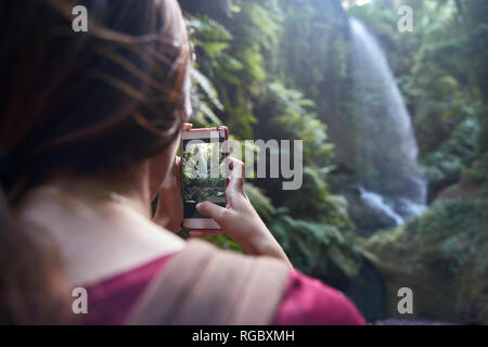 Espagne, Canaries, La Palma, femme en tenant un téléphone cellulaire avec photo d'une cascade dans une forêt Banque D'Images