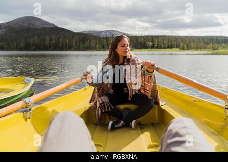 La Finlande, Laponie, femme portant une couverture dans une barque sur un lac Banque D'Images